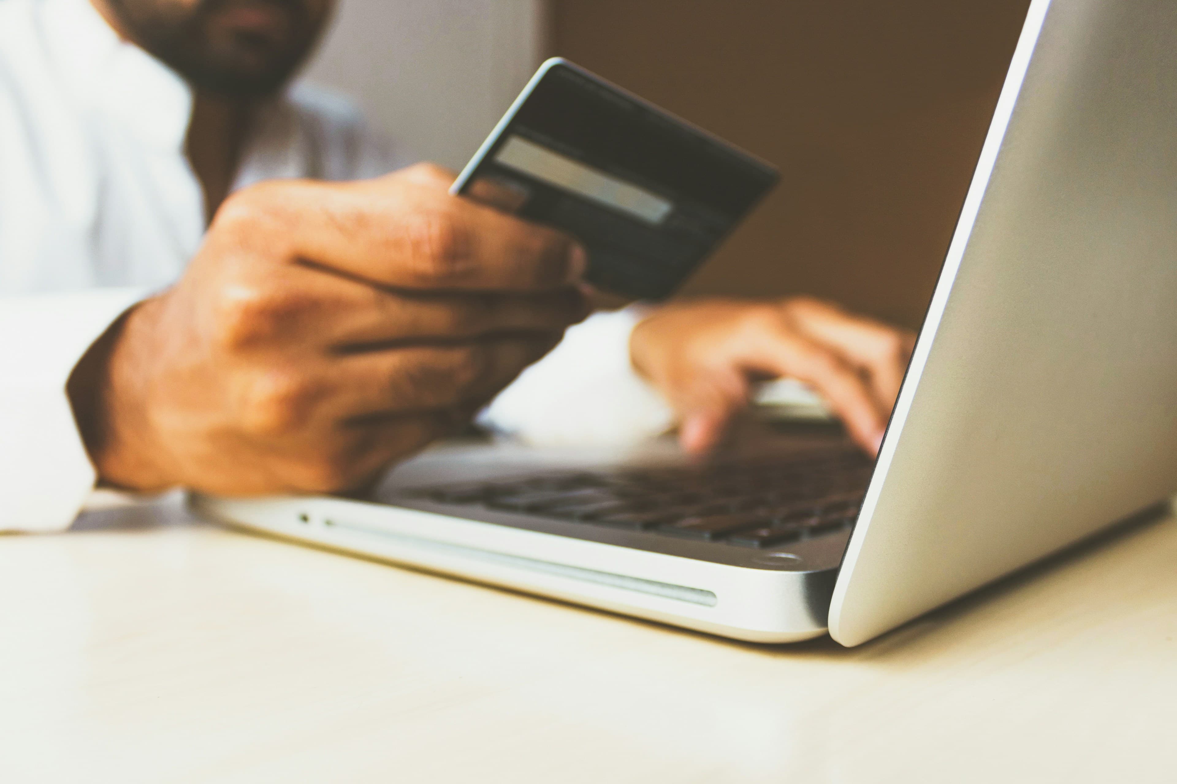 Person holding a bank card while using a laptop for business banking