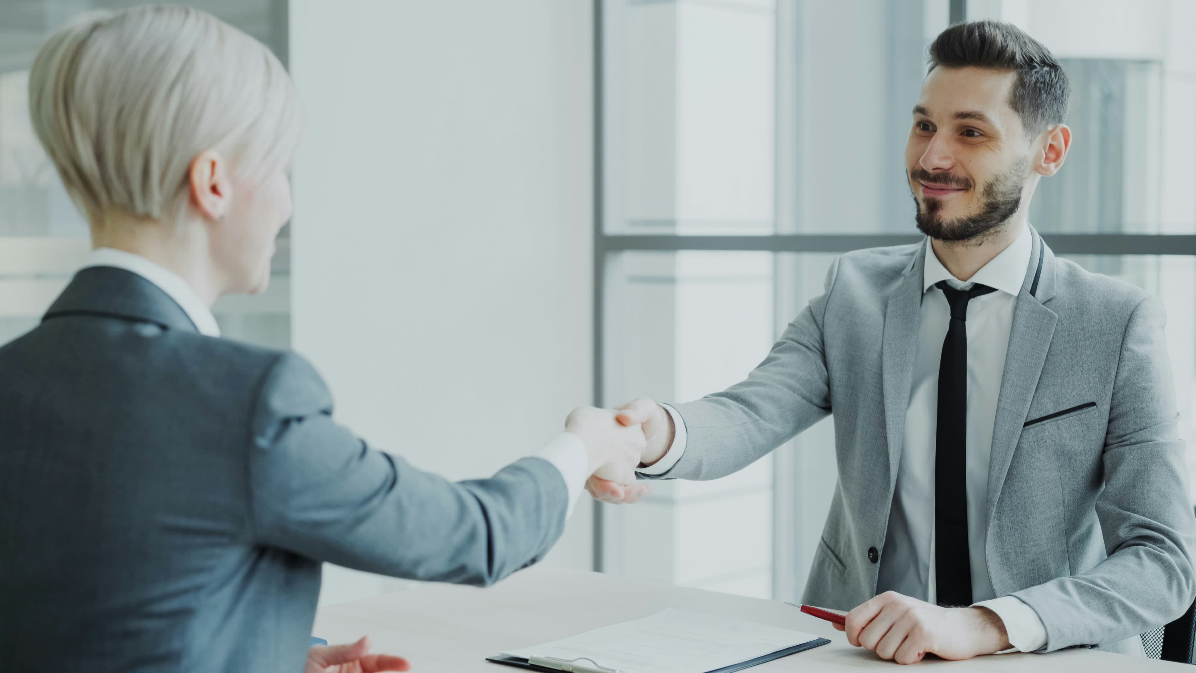Consultant shaking hands with a client across a desk
