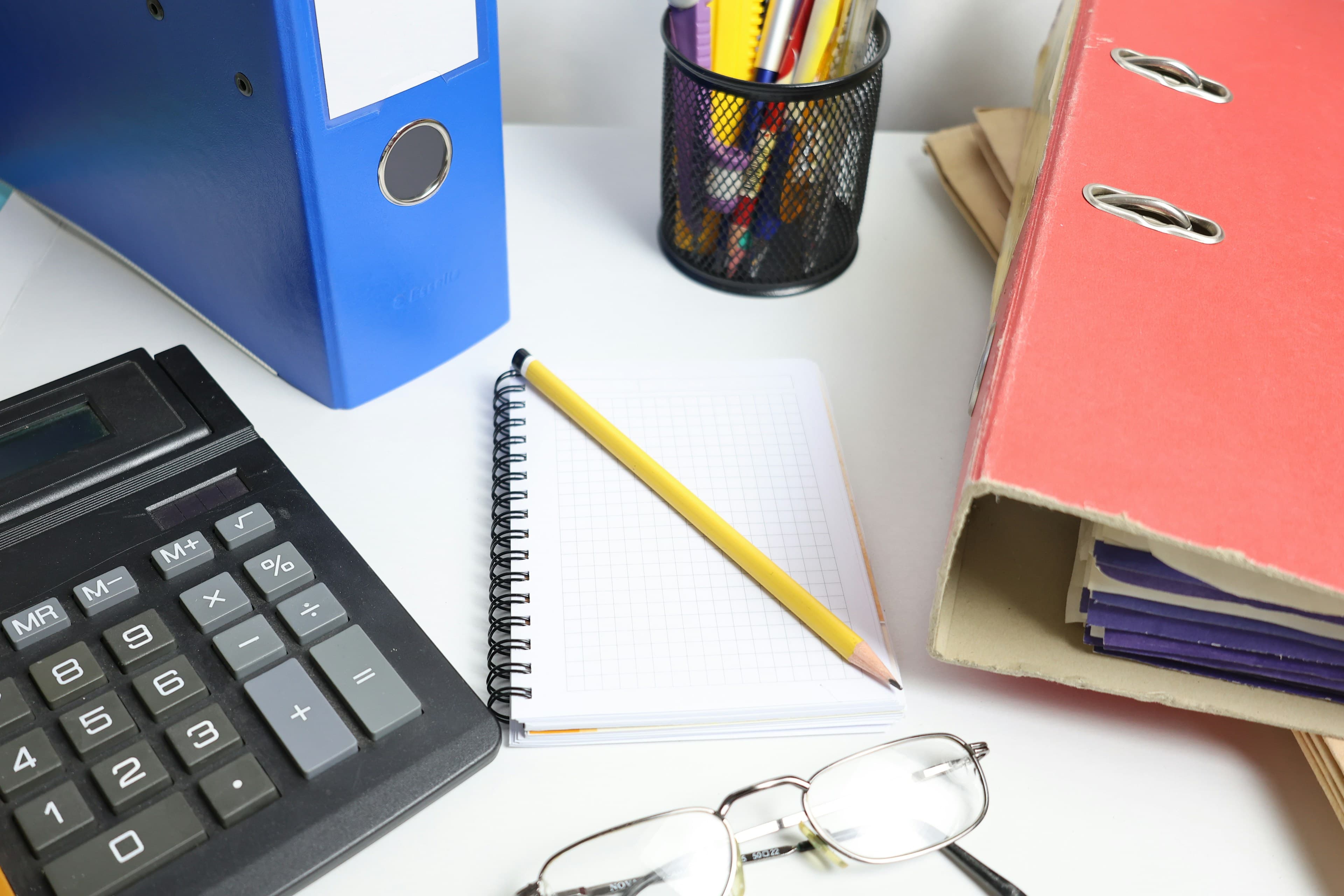 Office desk with document binders, a calculator and a notepad