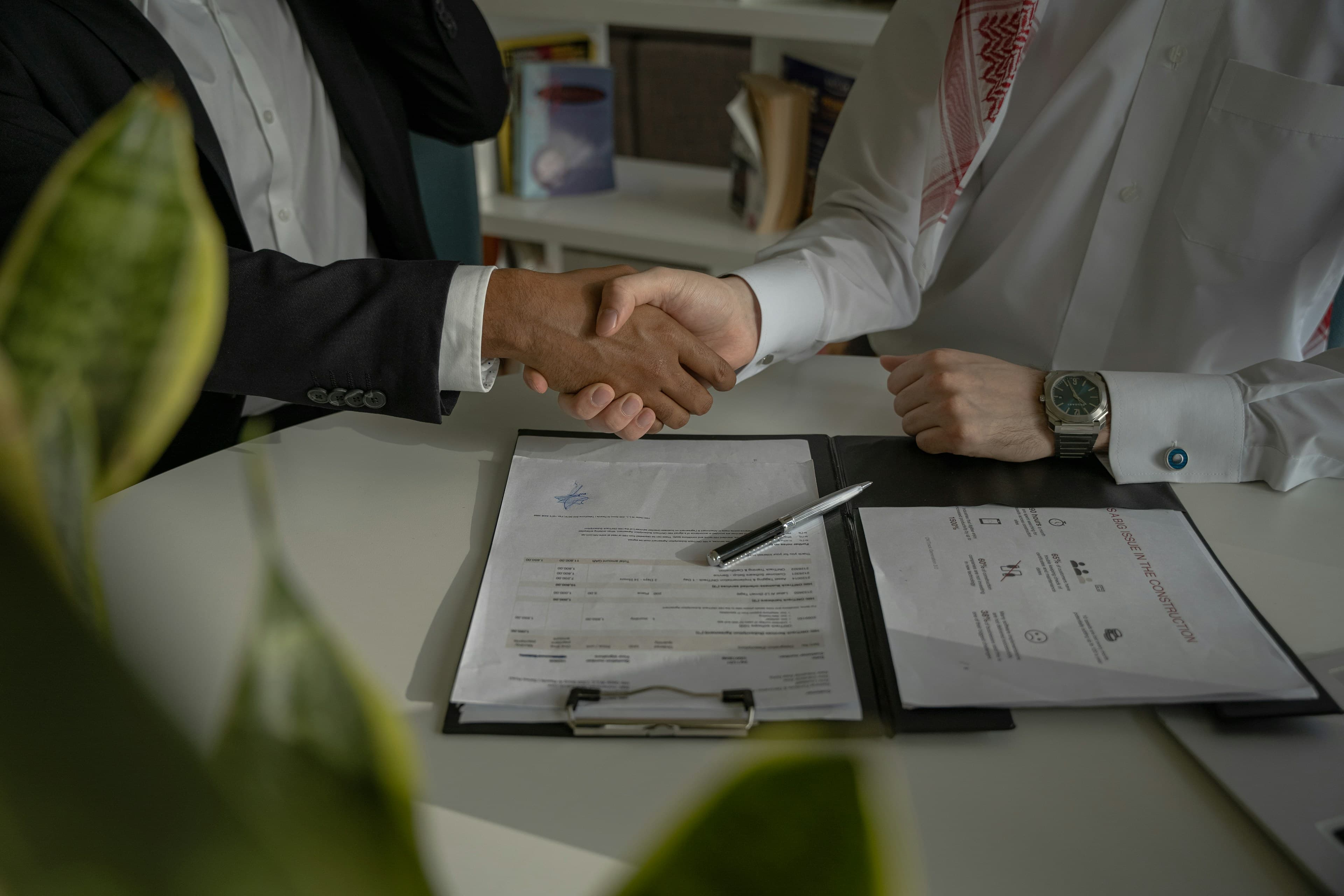 Business partners shaking hands over signed company documents